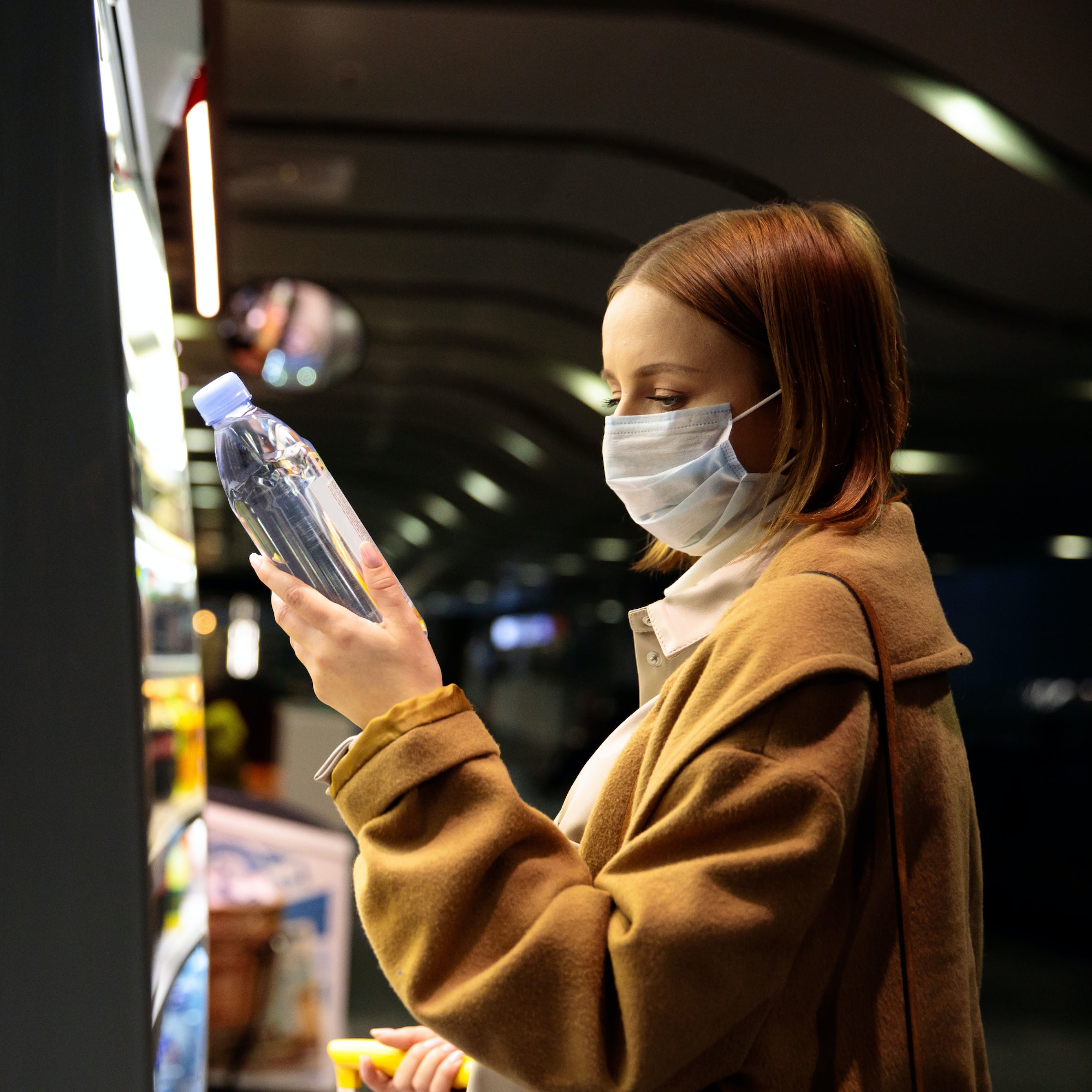 Woman customer wear face mask in airport, buying water bottle. Purchase of food during covid-19 Woman customer wear face mask in airport, buying water bottle. Purchase of food during covid-19