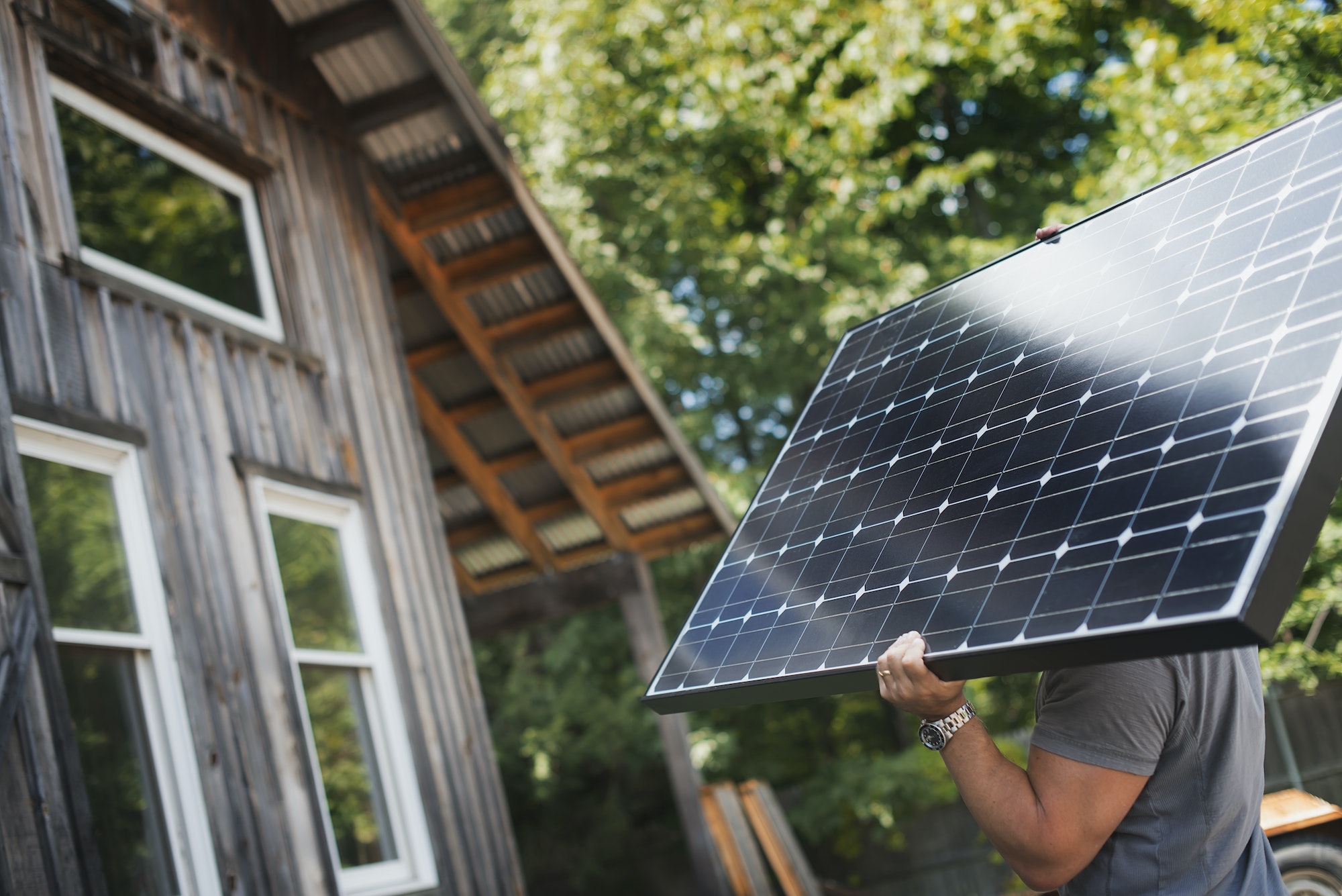 A man carrying a solar panel on a green construction site, working on a green building project.