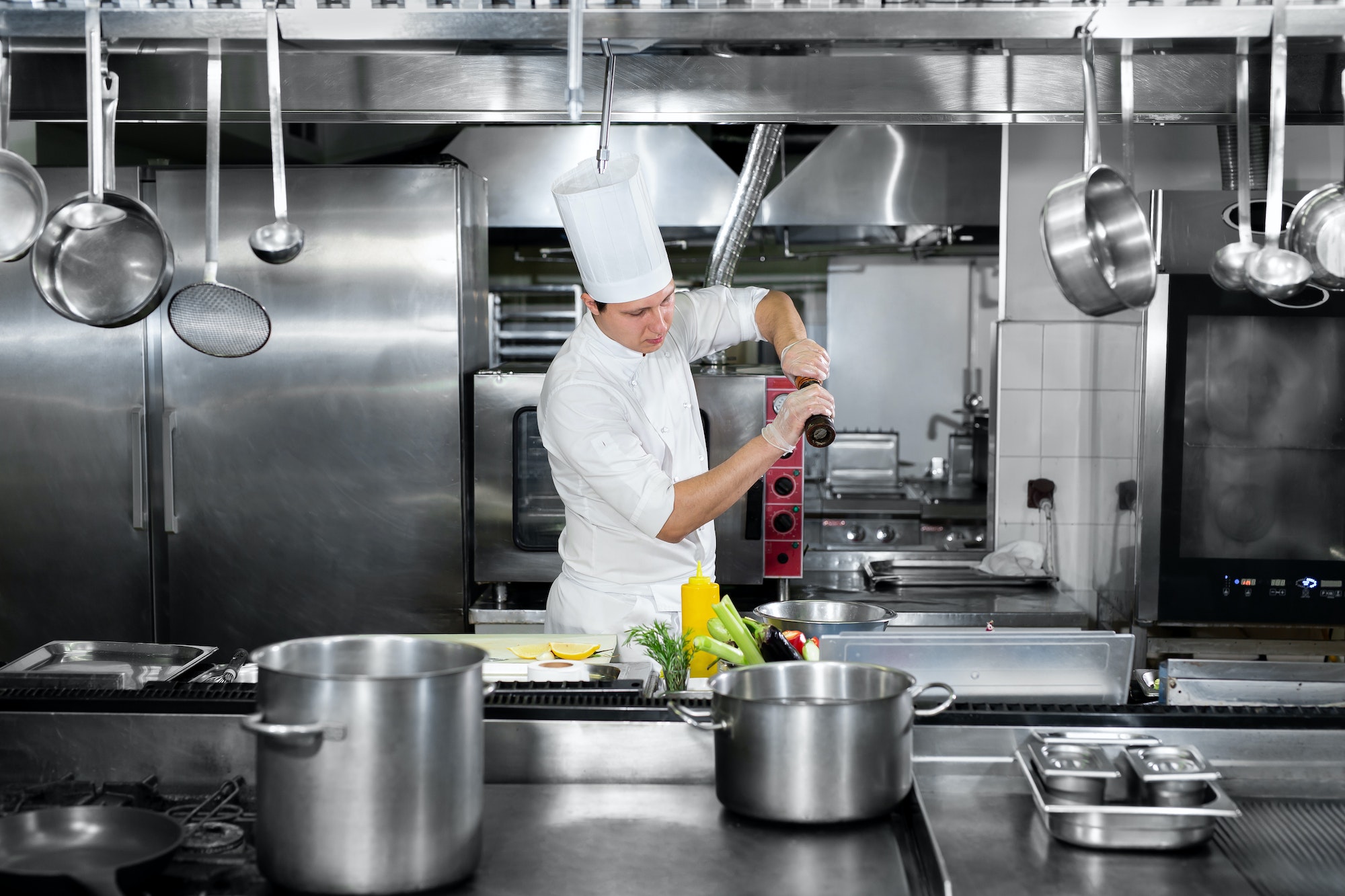Chef in hotel or restaurant kitchen cooking, he is seasoning dishes.