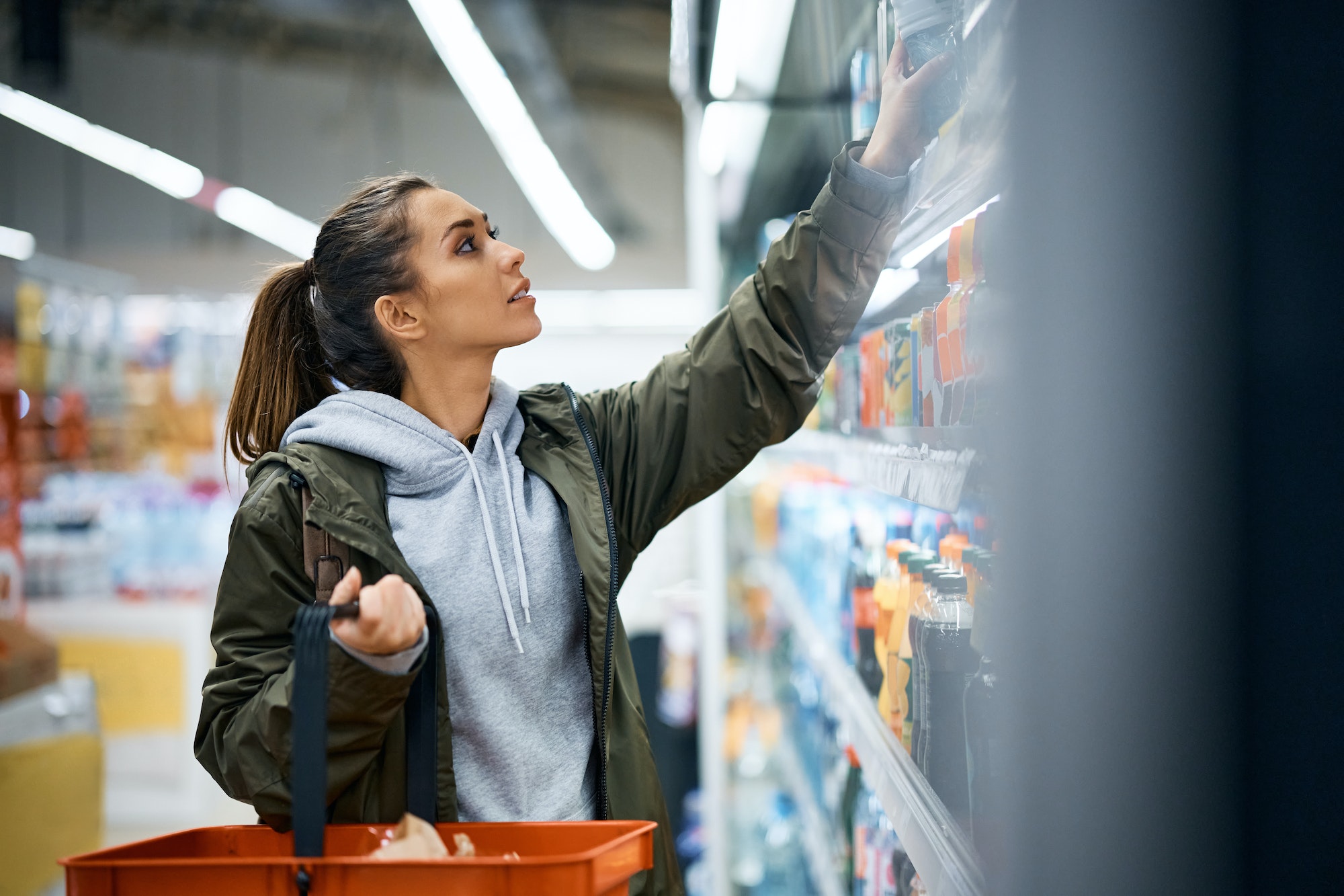 Young woman buying drinks in supermarket.